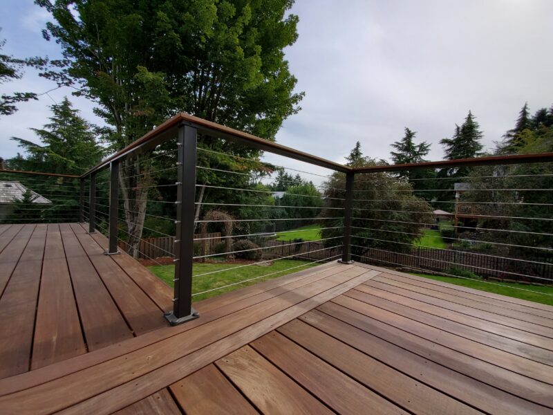 Cable railing with dark metal posts and wood top rail on an ipe hardwood deck